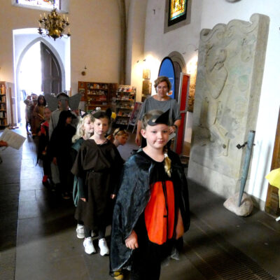 Foto in der Kirche. Der Blick schweift in Richtung Eingang, von dem aus die Kinder in ihren Tierkostümen der Reihe nach einmarschieren.