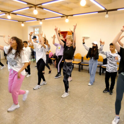 Im Bild sieht man eine Gruppe von tanzenden Schülern.