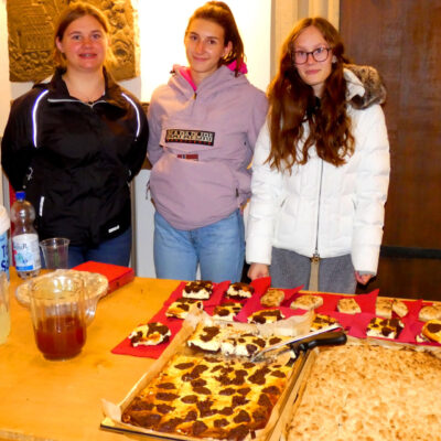 Im Bild sind drei junge Damen zu sehen, die sich um das Verteilen des Kuchenbuffets kümmern.