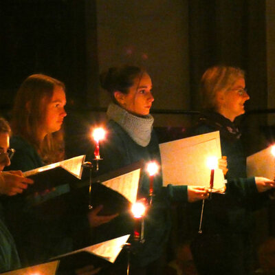 Im Bild sieht man junge Damen mit einer Kerze und Liedertexten.