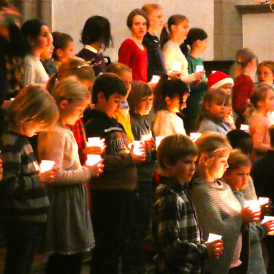 Im Bild sieht man eine Gruppe von Schülern und Schülerinnen, von denen jeder eine Kerze in den Händen hält.